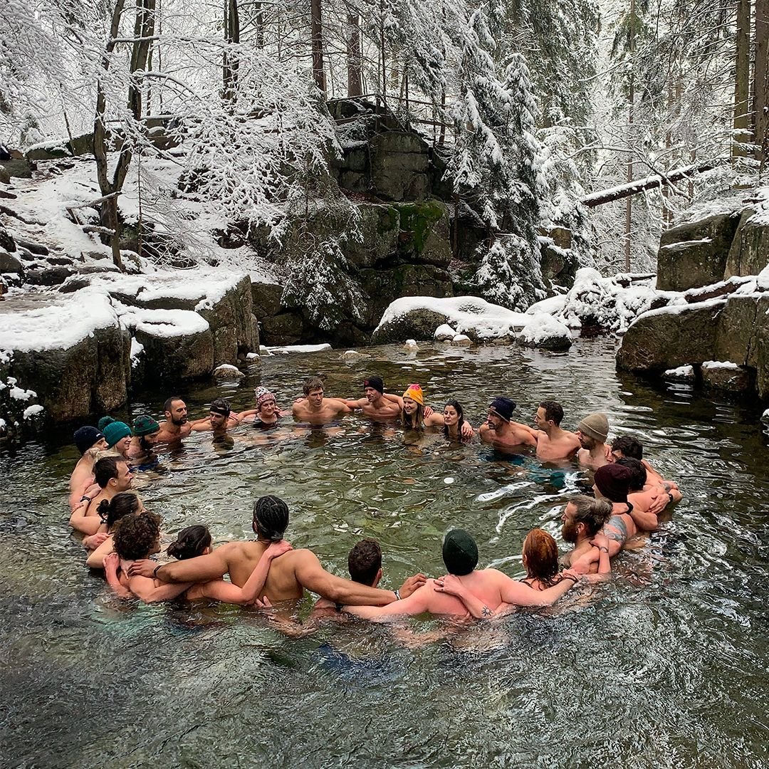 Retreat participants forming a circle in a snowy natural pool in Northern Sweden